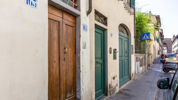 A narrow street with traditional buildings, a pedestrian crossing sign, and a parked car. - GuestHost - Boboli Gardens Lovely Apartment (Firenze)