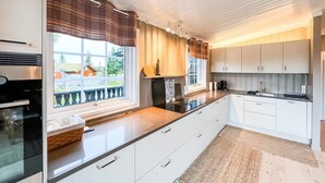 Een moderne keuken met witte kastjes, een groot raam en uitzicht op de omgeving.