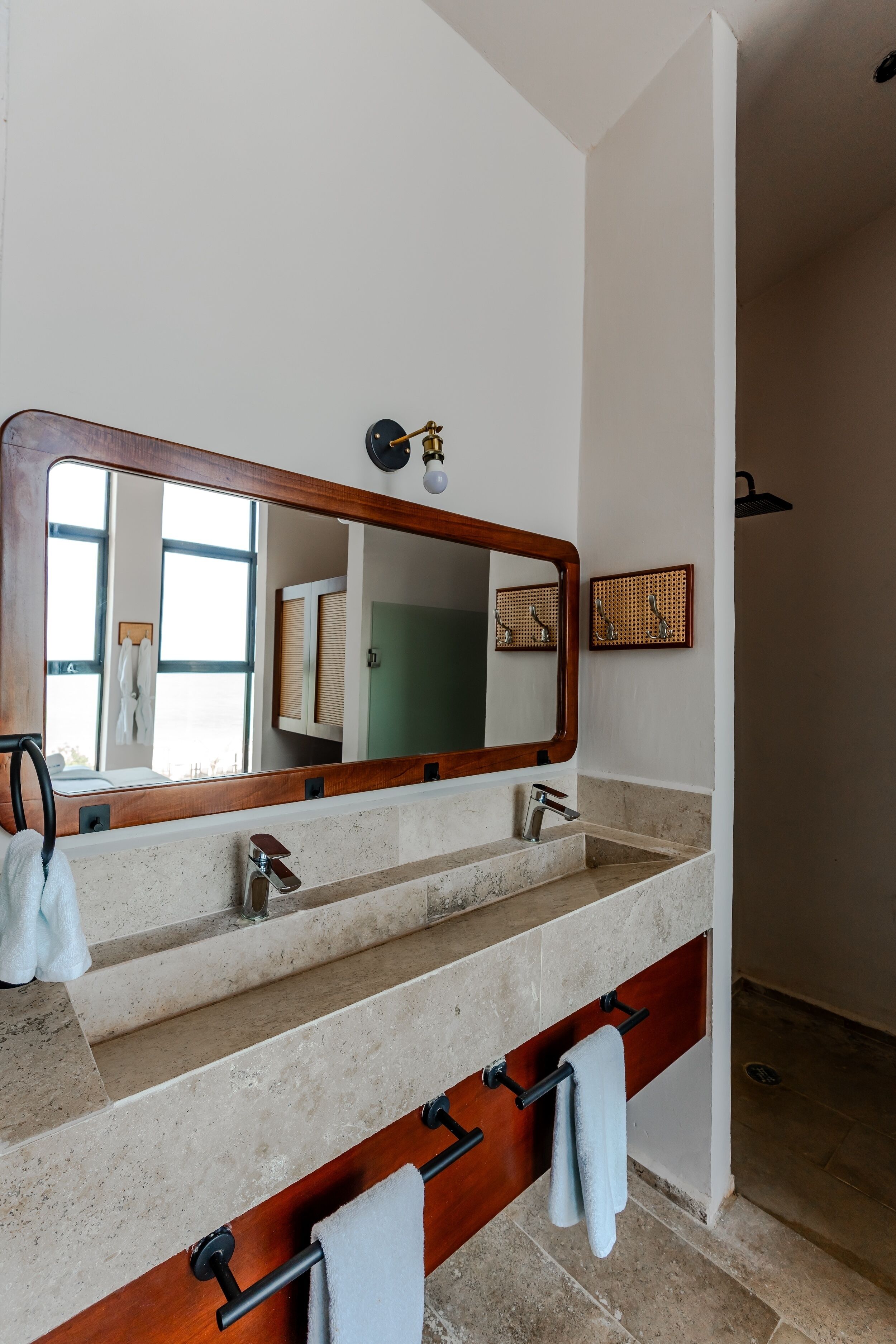 A bathroom with a large mirror, two sinks, and a towel rack.