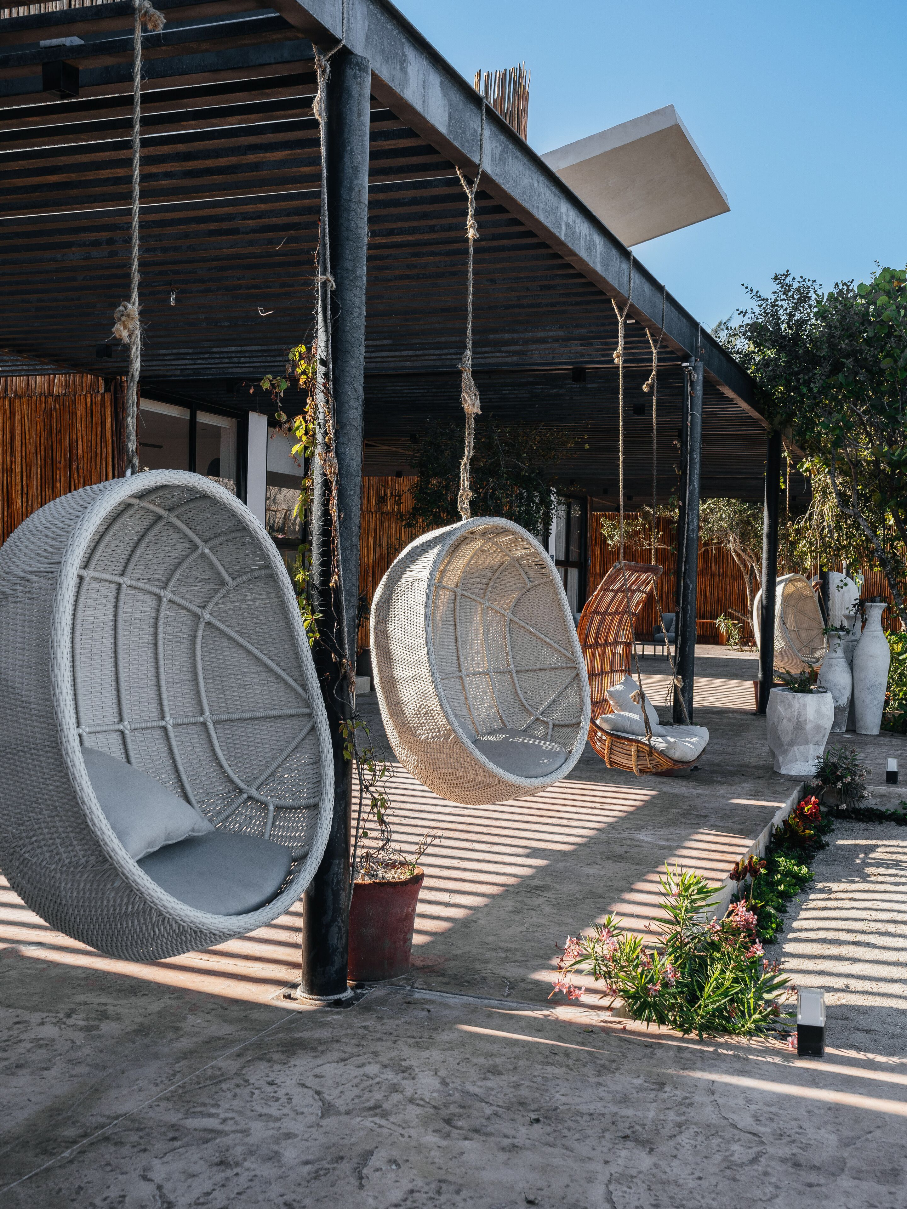 A covered outdoor seating area with wicker chairs and a hanging chair.