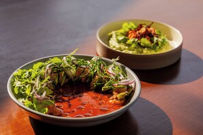 Two bowls of food on a wooden table.