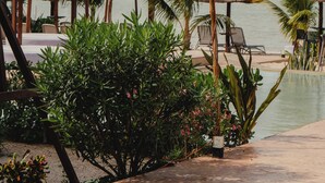 A resort pool area with lounge chairs, thatched umbrellas, and string lights.