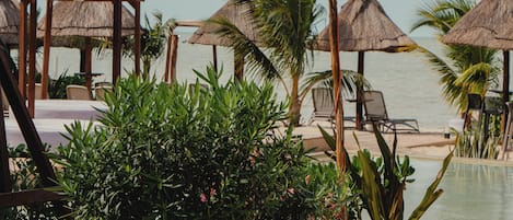 A resort pool area with lounge chairs, thatched umbrellas, and string lights.
