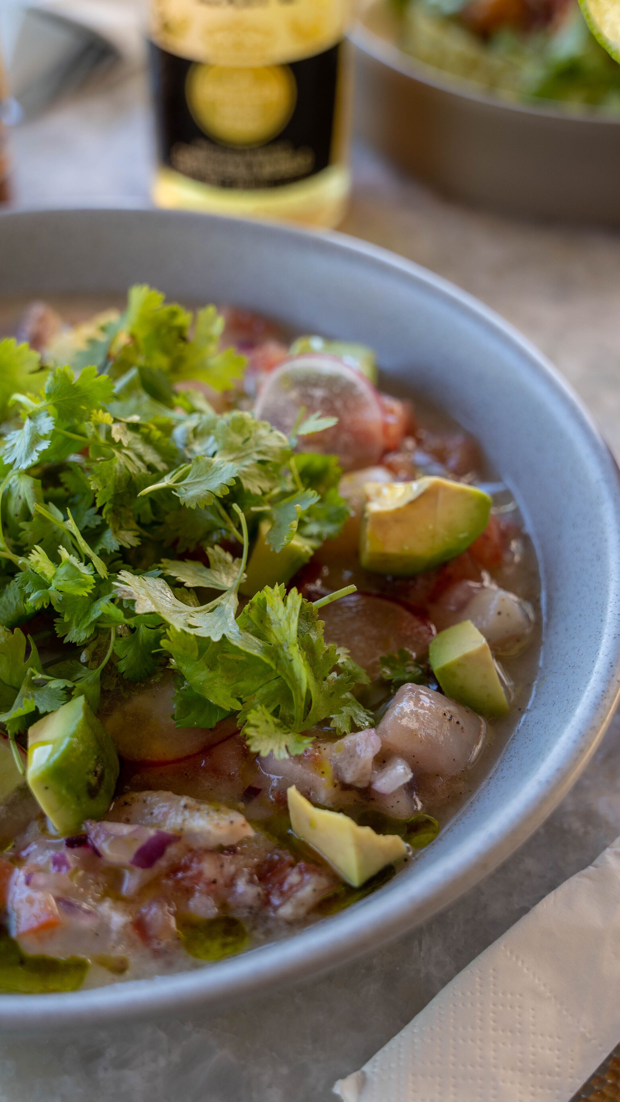 Un tazón de sopa adornado con aguacate y cilantro.