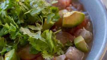 Un tazón de sopa adornado con aguacate y cilantro.