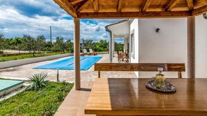 Un'area esterna coperta con piscina, mobili in legno e un tavolo con un oggetto decorativo.