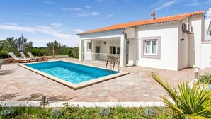 Una villa moderna con piscina, patio coperto e giardino.