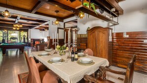 Zona de menjador amb billar, cadires de fusta i taula preparada per a dinar.