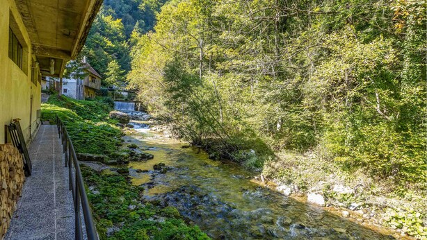 Un sender de pedra estret que condueix a un edifici rústic amb una petita cascada.