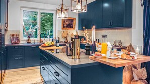 A modern kitchen with dark cabinetry, a central island, and a breakfast setup. - 3 bedroom beautiful home in Wartenberg (Wartenberg)