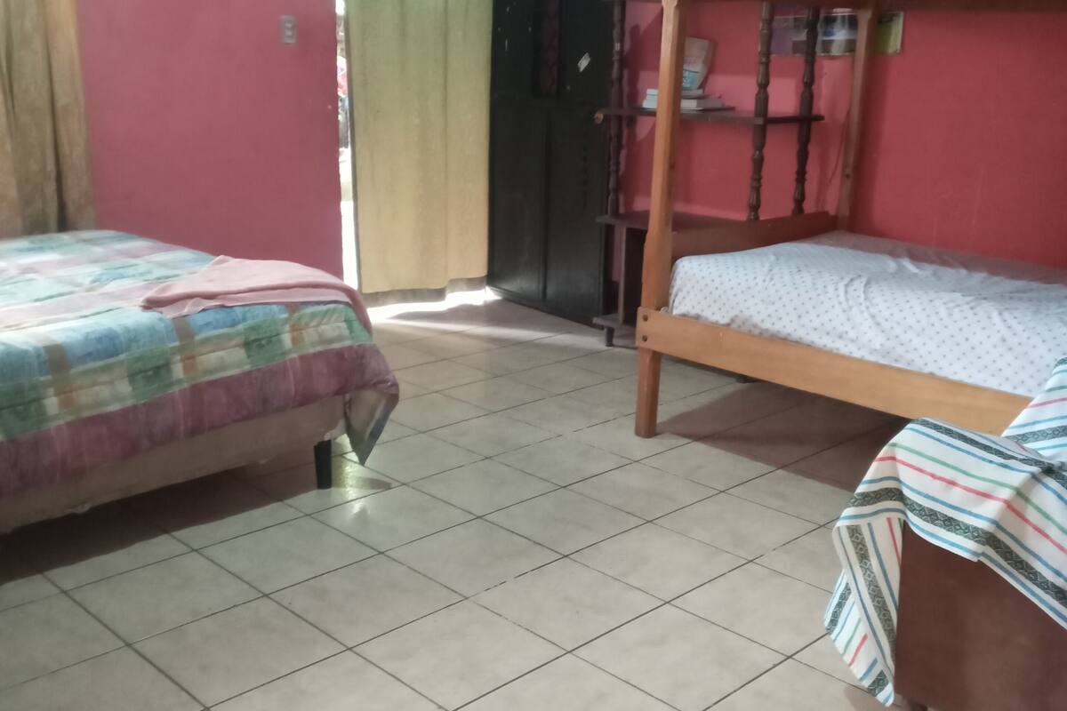A bedroom with two beds, a wardrobe, a television, and a door.