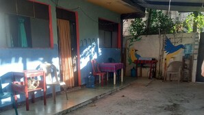 Una habitación con suelo de hormigón, una mesa con sillas, un dispensador de agua y un mural de pájaros en la pared.