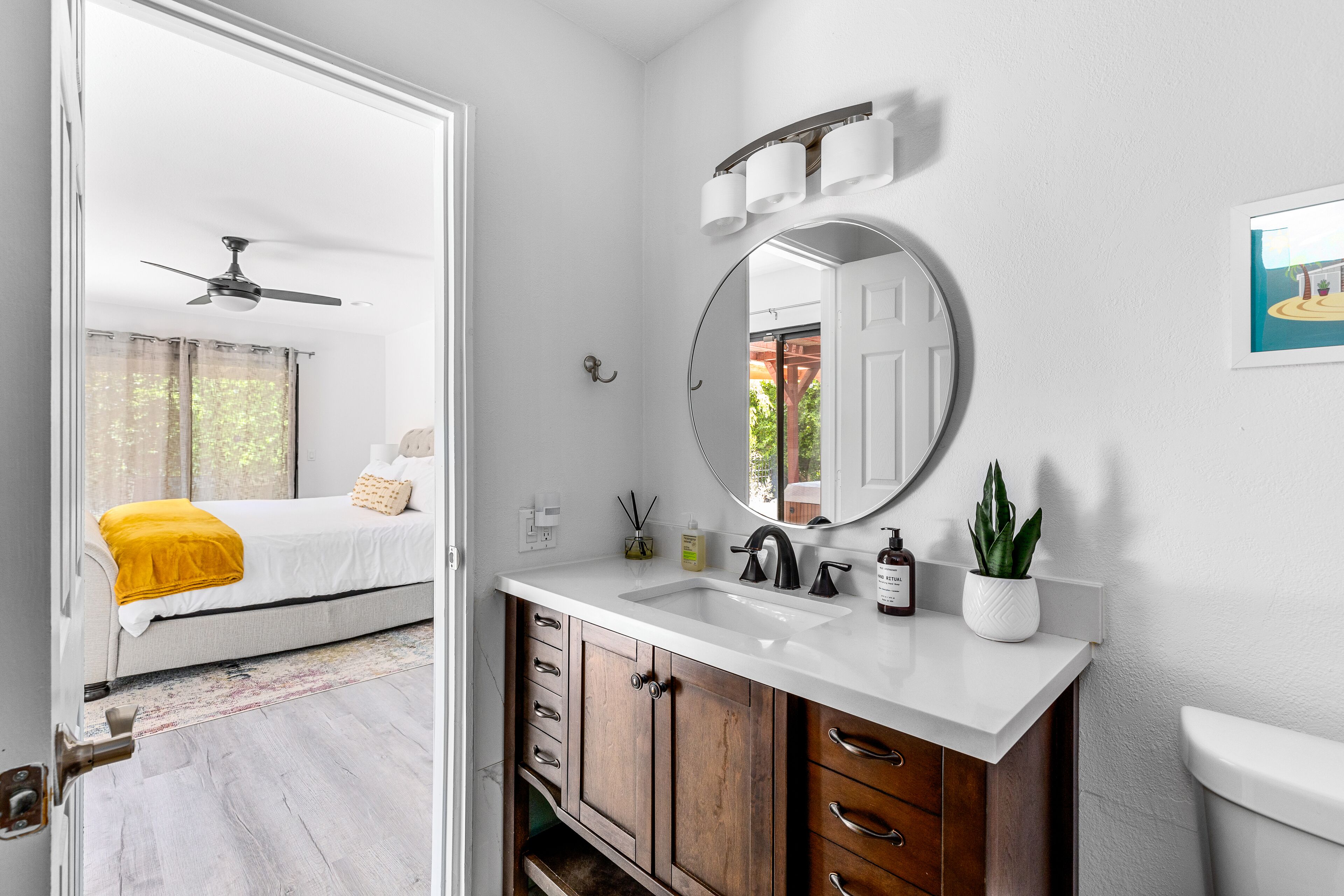 Een badkamer met een witte wastafel, een ronde spiegel en een toilet.