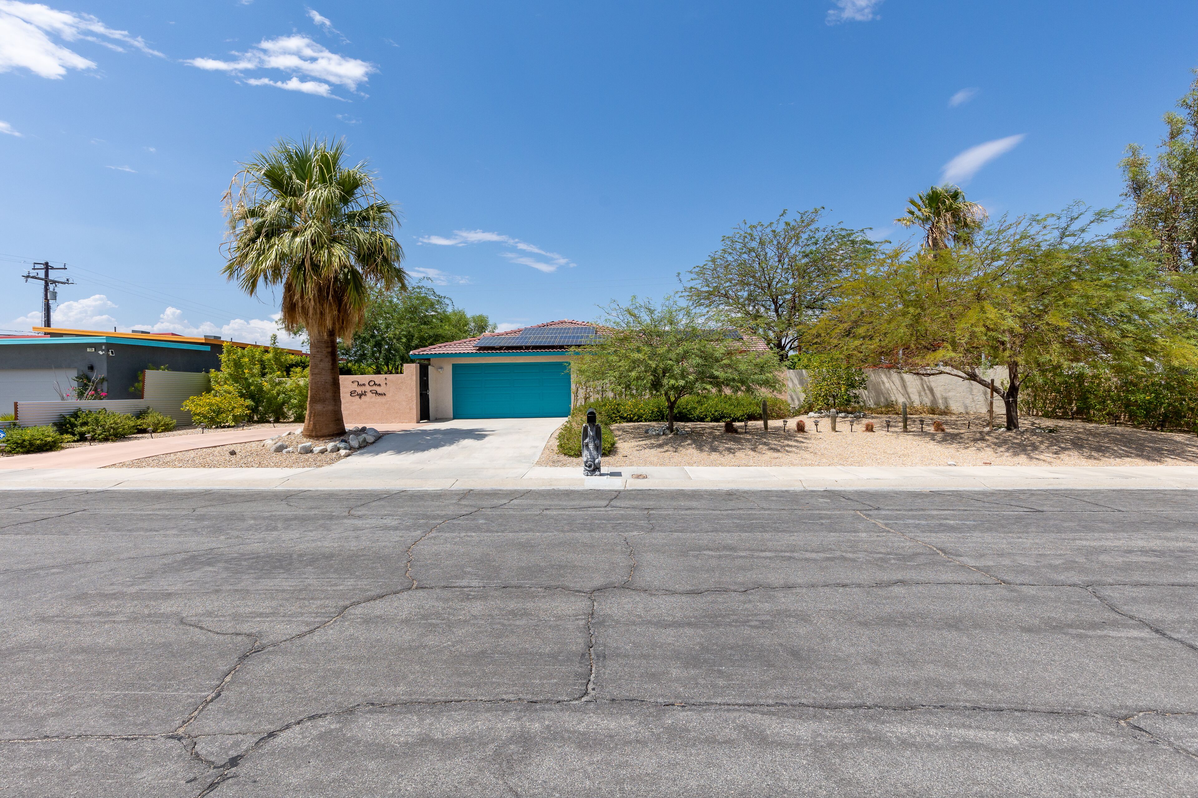 A residential area with a garage, a palm tree, and a clear sky.