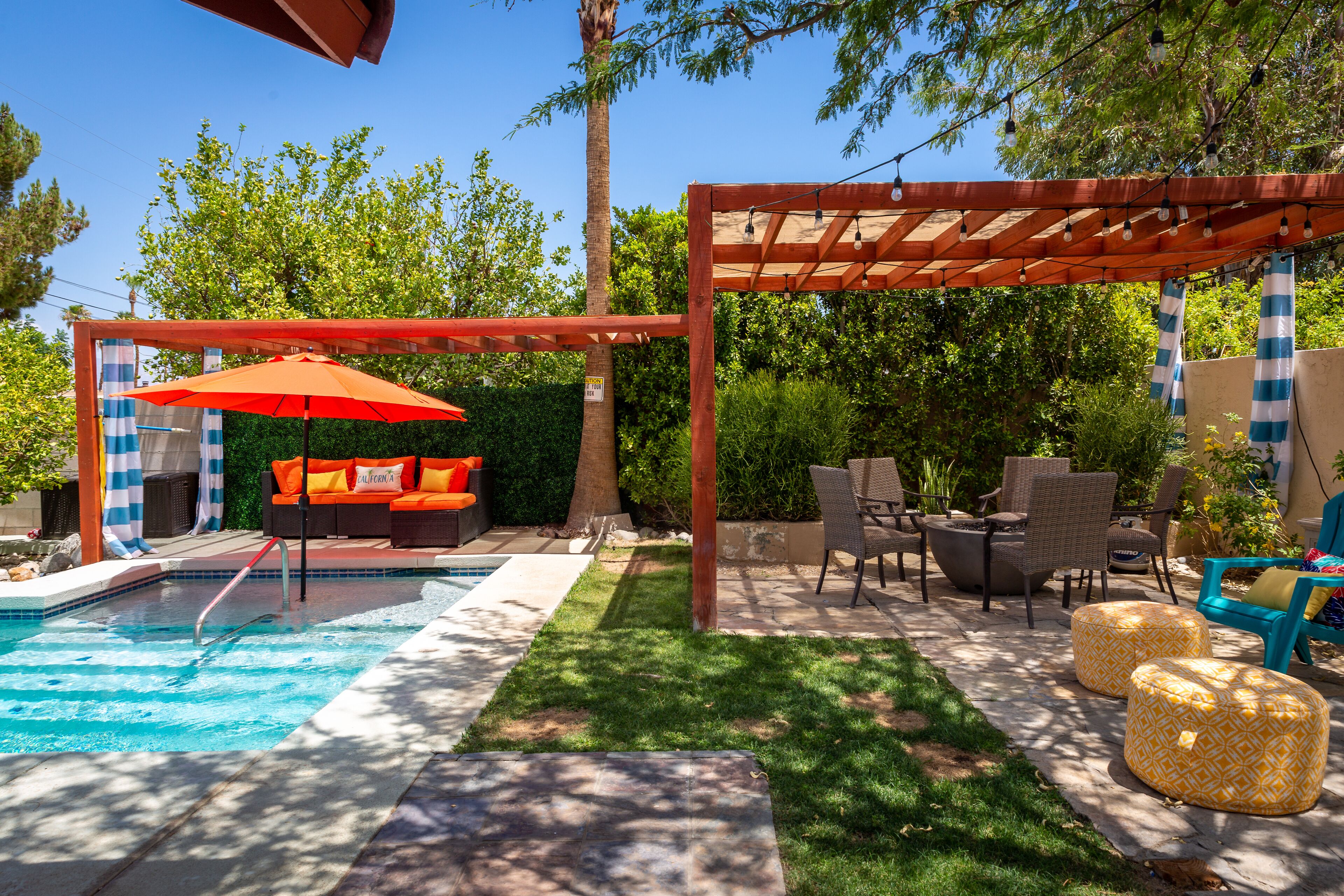 A backyard with a swimming pool, outdoor seating, and a pergola.