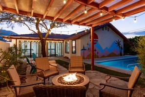 An outdoor patio with wicker chairs, a fire pit, and a swimming pool. - Palm Paradise  (Palm Springs)