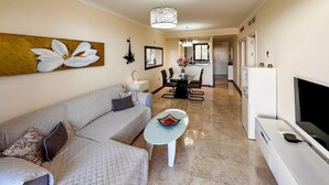 A modern living room with a sofa, a coffee table, a TV, and a dining area in the background. - Awesome apartment in LA CALA DE MIJAS (MIJA (LA CALA DE MIJAS (MIJA)