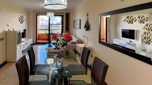 A modern dining area with a glass table, chairs, a vase with flowers, a television, and a large mirror on the wall. - Awesome apartment in LA CALA DE MIJAS (MIJA (LA CALA DE MIJAS (MIJA)