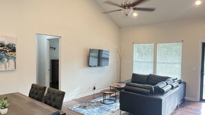 A spacious living area with a dining table, sofa, and ceiling fan.