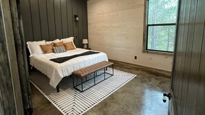 Un dormitorio con cama, banca y ventana.