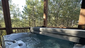Un jacuzzi con muelle de madera y vista al bosque.