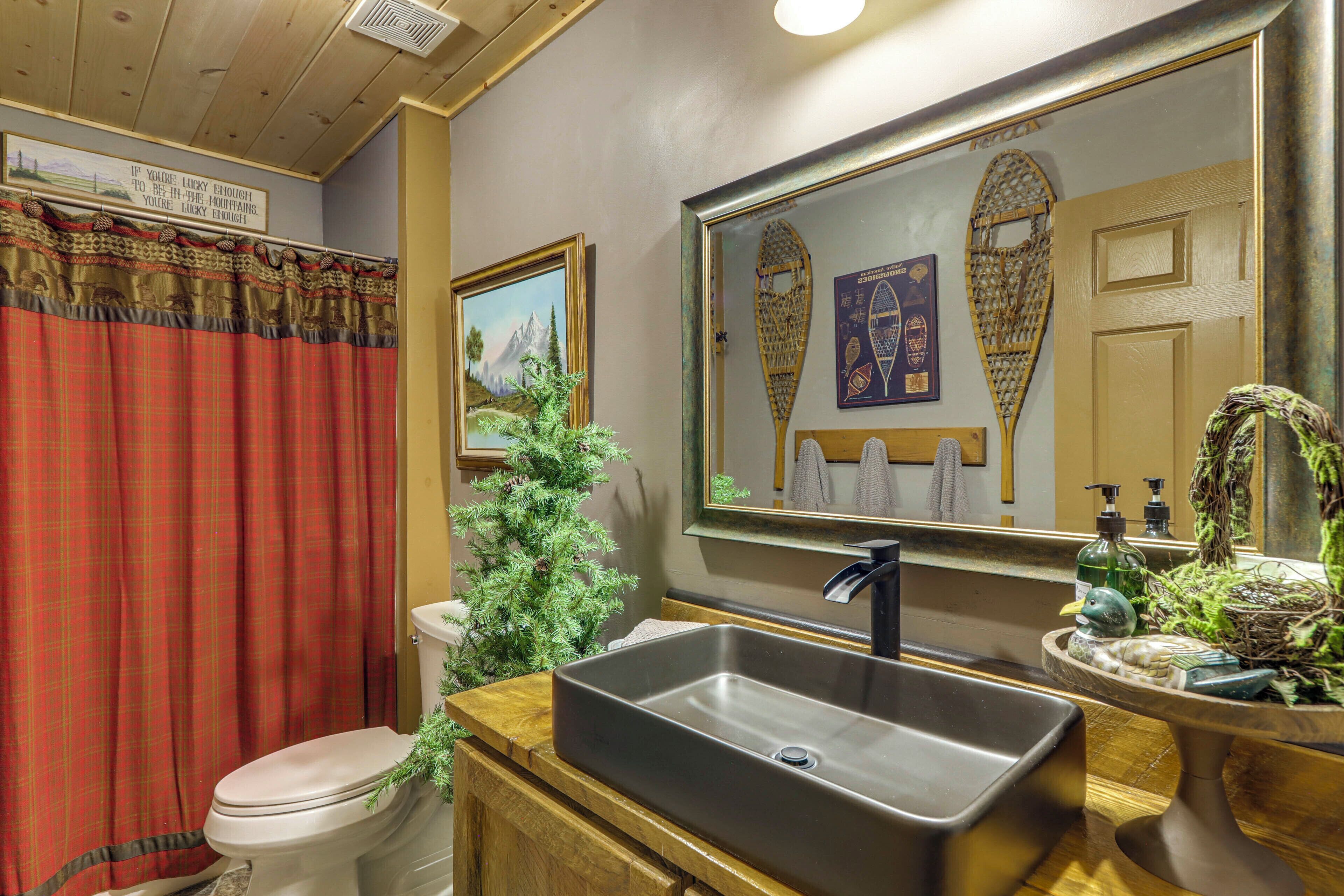 Un baño con inodoro, lavabo, espejo y detalles decorativos.
