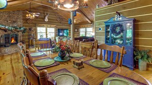 A wooden dining room with a fireplace, a blue cabinet, and a chandelier.