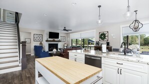 A modern kitchen with white cabinetry, a wooden island, and a large window providing a view of the outdoors.