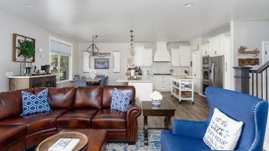 A spacious living room with a brown leather sofa, a blue armchair, and a wooden coffee table.