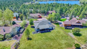 An aerial view of a residential area with houses, a large grassy field, and a lake in the background.
