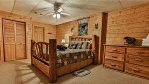 Une chambre à coucher de style chalet, avec un lit en bois, une commode et un ventilateur de plafond.