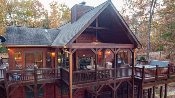 Une cabane en bois dotée d’un balcon et d’une terrasse, entourée d’arbres.