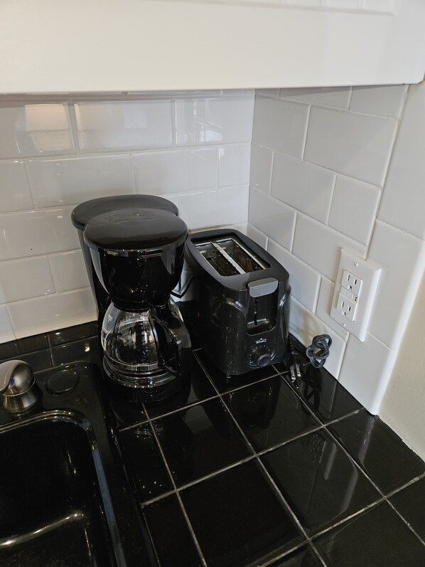 A kitchen with a black countertop, a coffee maker, a toaster, and a sink. - Ocean villa just steps away from the pool and beach (Hilton Head Island)