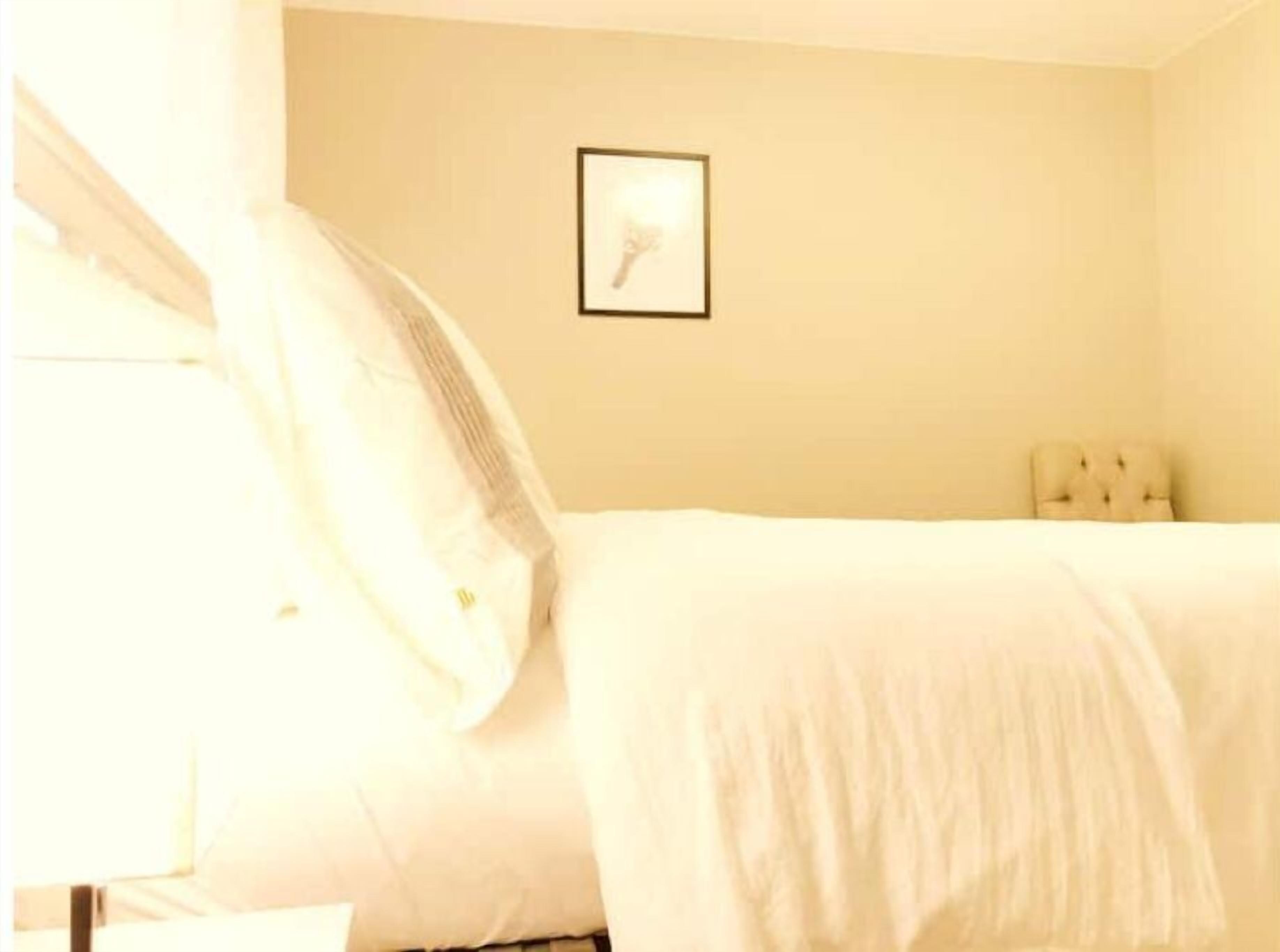 A bedroom with a bed, a headboard, and a framed picture on the wall.