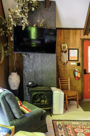 A cozy room with a fireplace, a vintage radio, a chair, and a colorful rug. -  Ski Out Chalet at Whitecap Mountain w/ full wrap around deck Pet-Friendly (Upson)