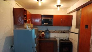 A compact kitchen with a refrigerator, microwave, stove, and cabinets. - Casa de Fabrizio en Cusco, Ideal Para Familias (Cusco)