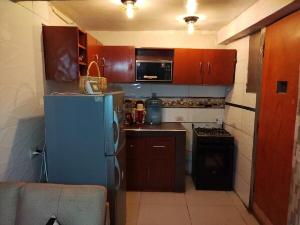 A compact kitchen with a refrigerator, microwave, stove, and cabinets.