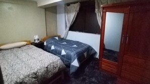 A bedroom with a bed, a nightstand, a wardrobe, and a window with curtains. - Casa de Fabrizio en Cusco, Ideal Para Familias (Cusco)