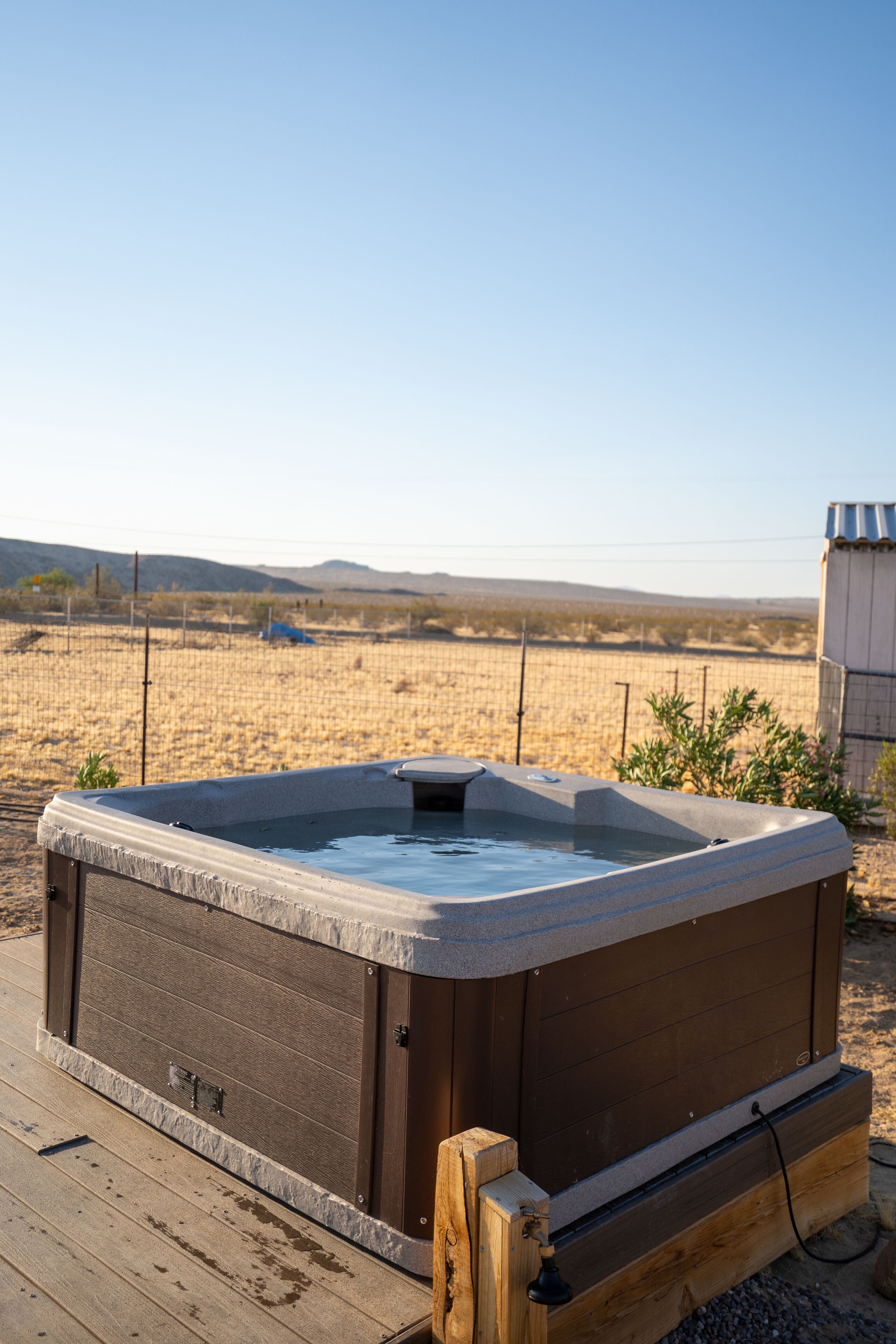 A hot tub on a wooden deck with a desert landscape in the background.