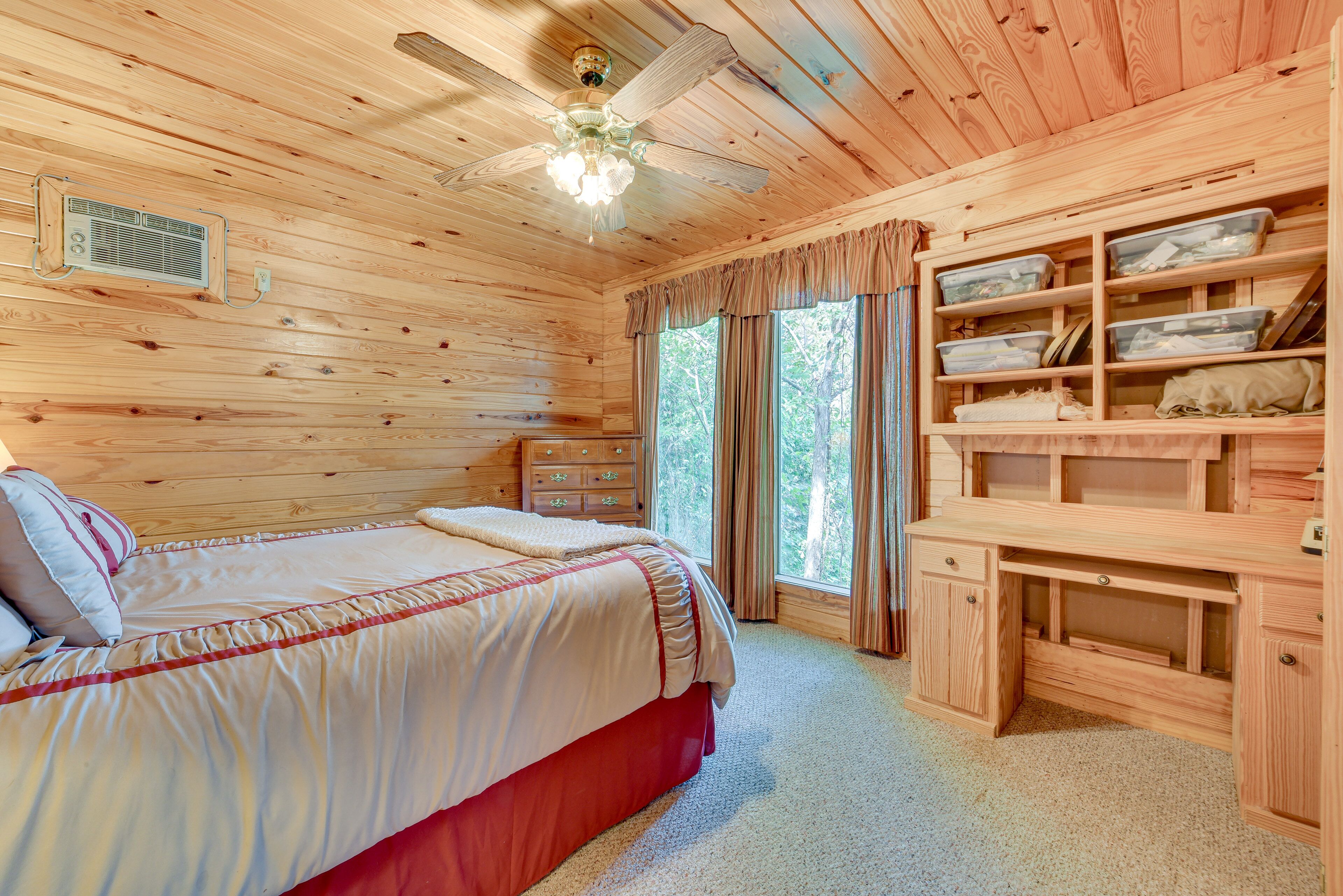 A wooden cabin bedroom with a bed, dresser, and built-in shelving.