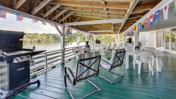 A covered outdoor deck with a grill, chairs, and a view of a lake. - Waterfront Jonesville Studio on Black River Lake! (Jonesville)