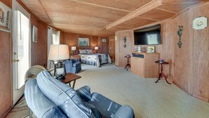 A cozy room with a bed, a sofa, a TV, and a small table with a lamp. - Waterfront Jonesville Studio on Black River Lake! (Jonesville)