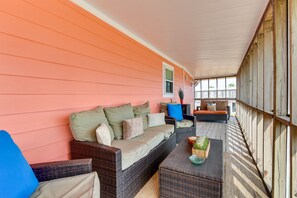 A covered porch with wicker furniture, a cushioned sofa, and a coffee table. - Steps to Surfside Beach: Home w/ Deck + Fire Pit! (Surfside Beach)