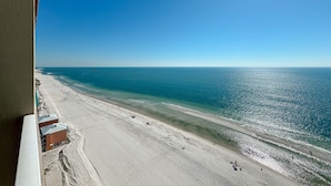 A beach view from a window overlooking a sandy beach with a clear blue sky and calm sea. - Crystal Shores West 1402 | Beachfront Penthouse | Pools, Fitness, Sauna | Beach Getaways (Gulf Shores)