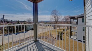 Ein Balkon mit Blick auf eine Wohngegend, einen klaren Himmel und eine ferne Stadtlandschaft.