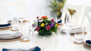 A dining table set with plates, glasses, and a centerpiece of colorful flowers. - Moonflower Villa: Luxe Oasis in Sunset Crest, Holetown (Sunset Crest)