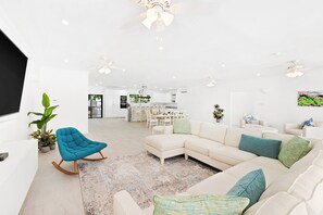 A modern living room with a sectional sofa, a rocking chair, and a dining area in the background. - Moonflower Villa: Luxe Oasis in Sunset Crest, Holetown (Sunset Crest)