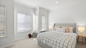A bedroom with a large bed, two bedside lamps, and a nightstand. - Jan Juc Surfview Beach House Beach, Golf & Cafes (Jan Juc)