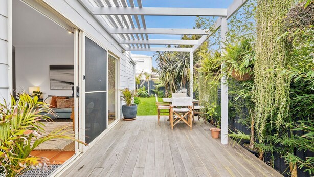 A covered patio with a wooden deck, a table and chairs, and a variety of potted plants. - Jan Juc Surfview Beach House Beach, Golf & Cafes (Jan Juc)