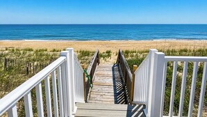Une promenade en bois qui mène à une plage, avec un ciel bleu dégagé.